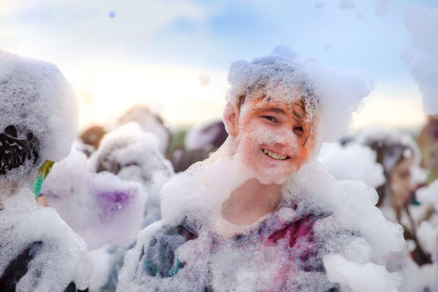 Kids laughing and playing in a foam party
